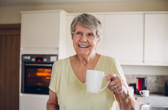 smiling adult at home in her kitchen. Links to client stories page.