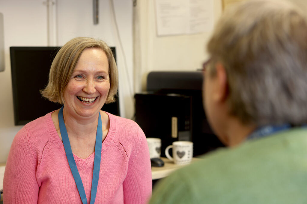 Smiling adult women in office chatting with another volunteer adviser.